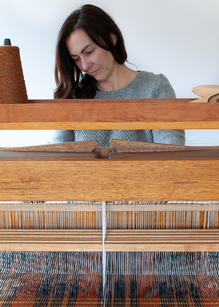 Textile designer Victoria Pemberton weaving on a floor loom in her home studio.