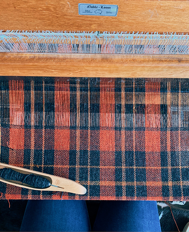 an overhead image of victoria pemberton weaving her fireside check design on a floor loom